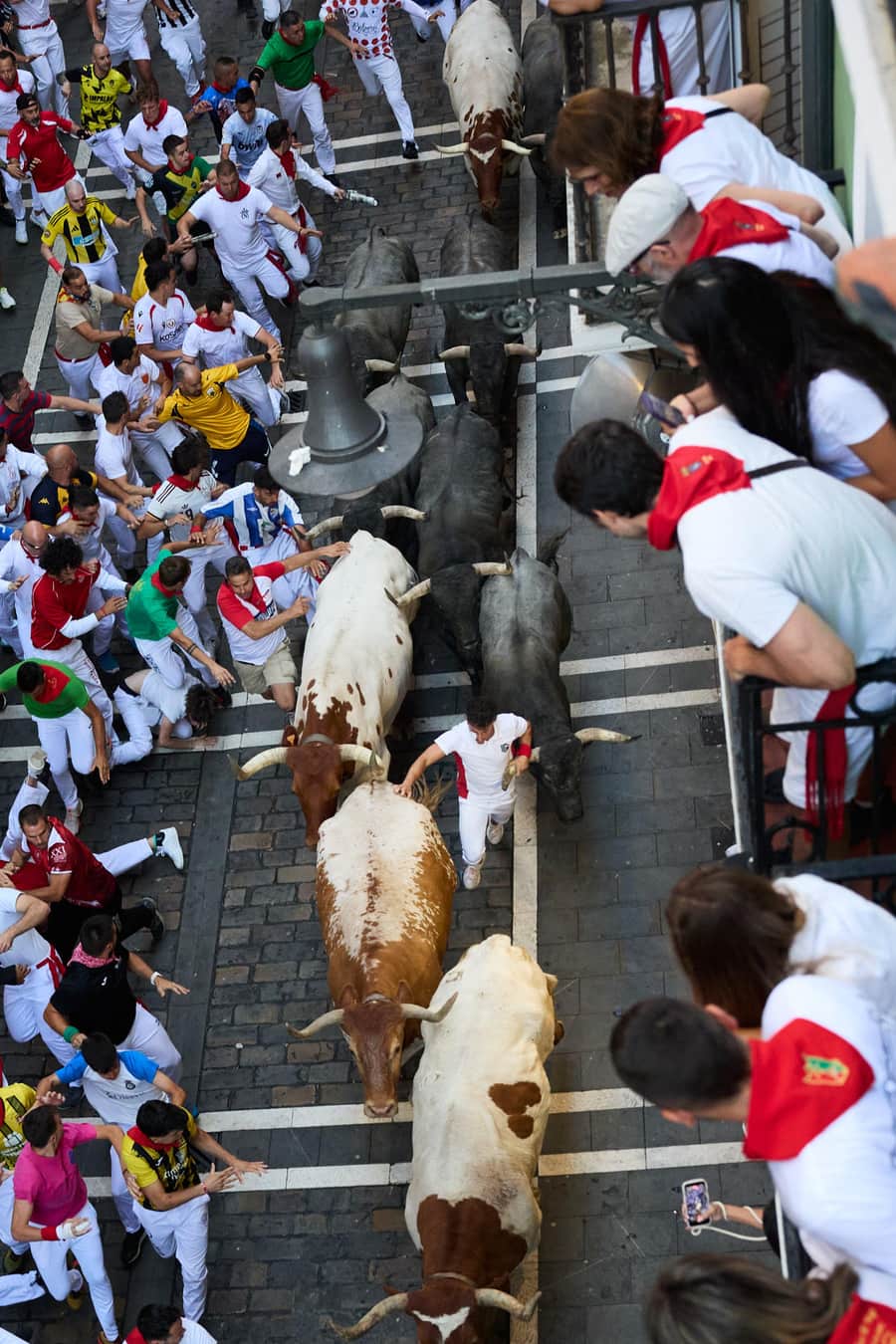Encierro de San Fermín visto desde un balcón en Pamplona con corredores y toros